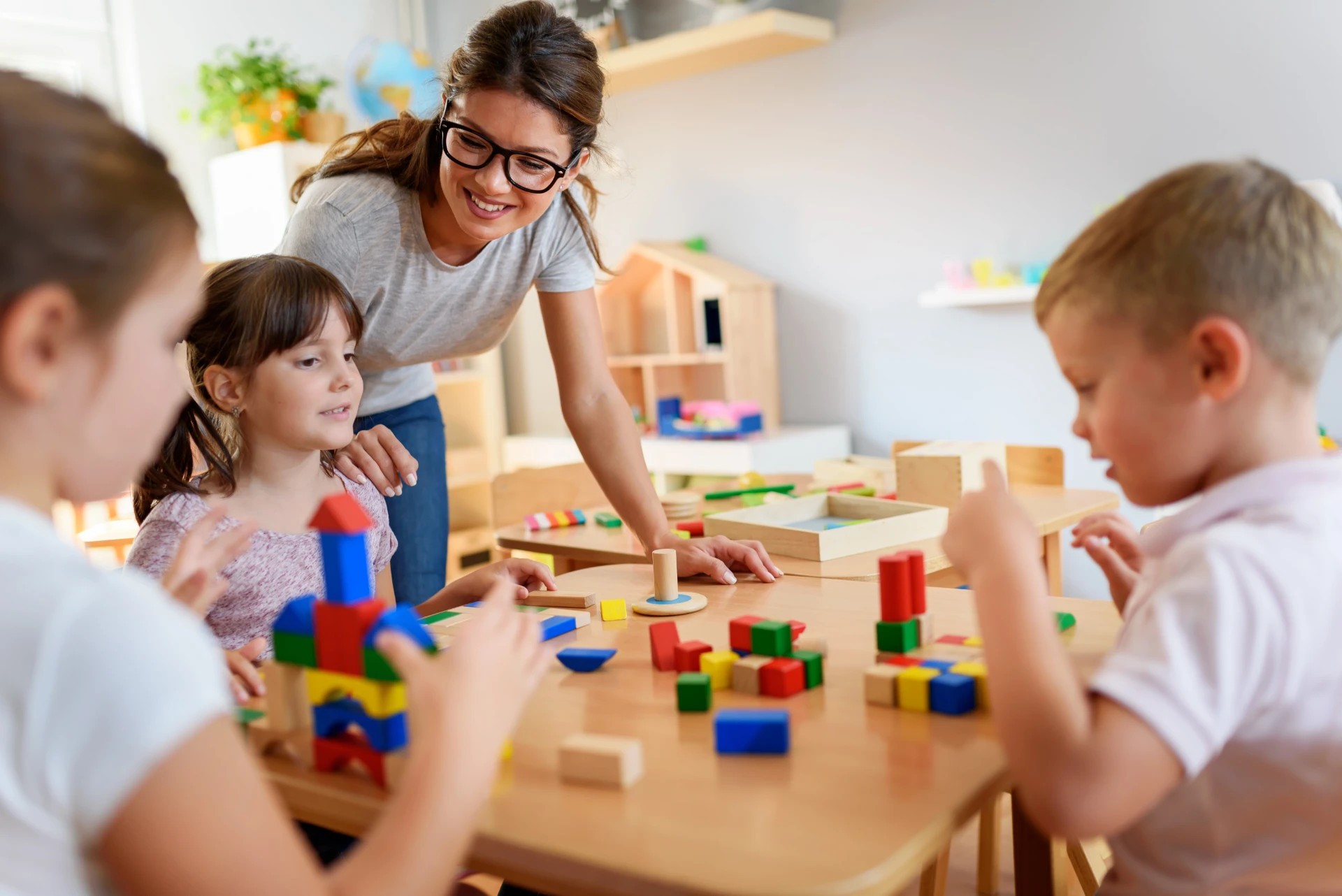 A teacher helping children explore colorful building blocks