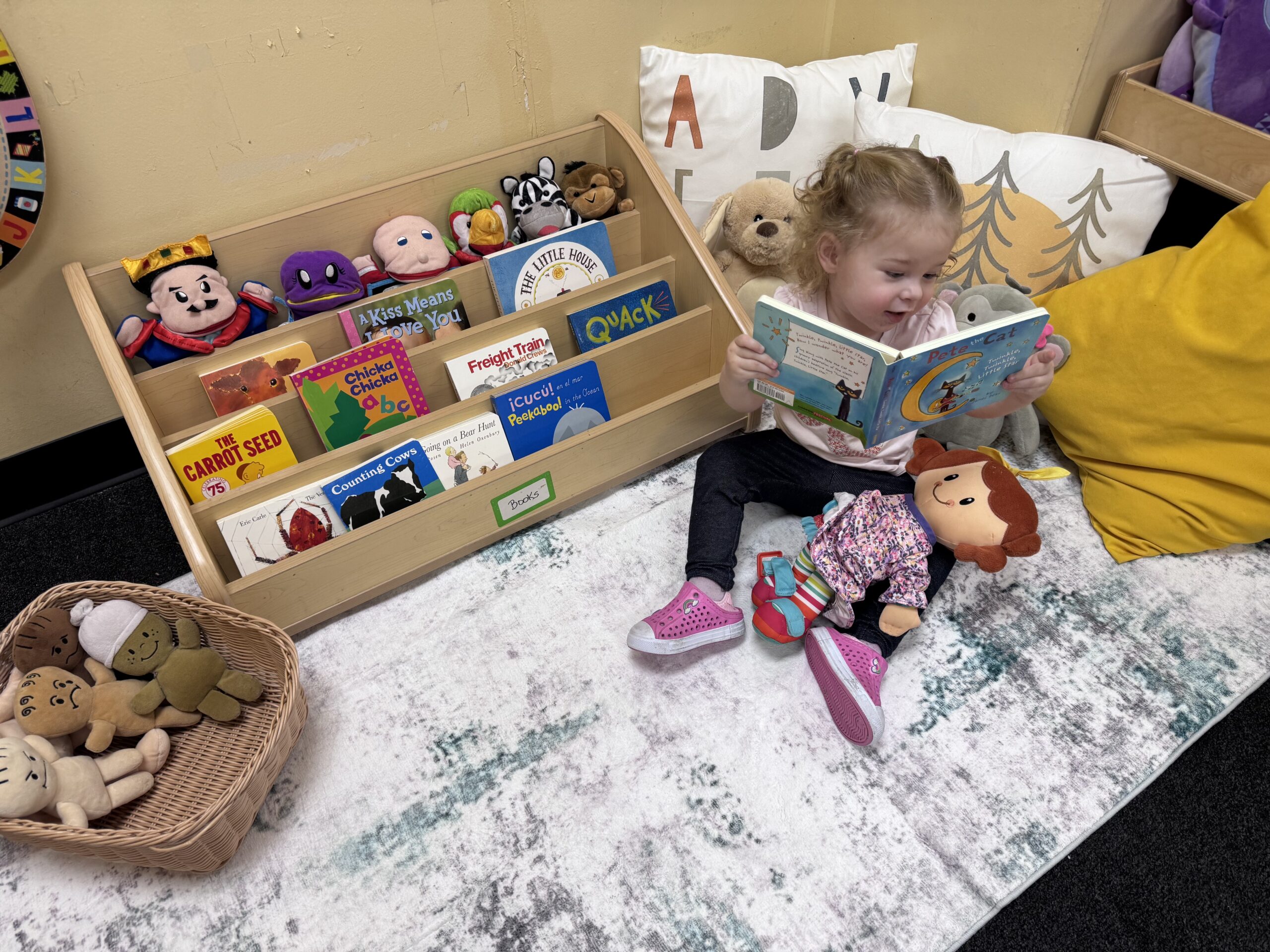 A child reading picture books in the cozy classroom library